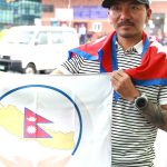 Mingma David Sherpa holding a flag with Nepal Parliament logo after Everest expedition