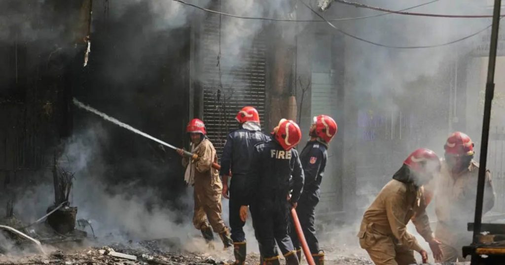 Firefighters battle a blaze outside a smoke-filled building in Delhi