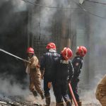 Firefighters battle a blaze outside a smoke-filled building in Delhi