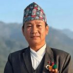 Harka Sampang posing outdoors in traditional Nepali attire with hills in the background