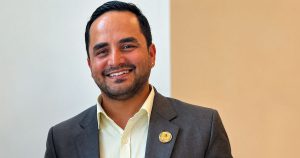 Som Sharma smiling in a suit during a posed portrait photograph