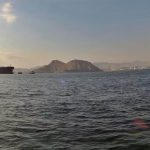 Oil tanker anchored off the coast near Oman with mountains visible across the Gulf waters