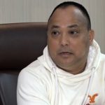 Rajesh Man Singh seated indoors during an interview, wearing a white hoodie