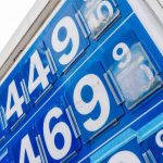 Gasoline price board at a US fuel station with an American flag in the background